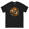 King of the Grind tee, black, front: illustration of a lion barista in a brown apron pouring latte art into a cup, with tamper, portafilter and grinder, framed by a gold circle with shelves of coffee bags behind